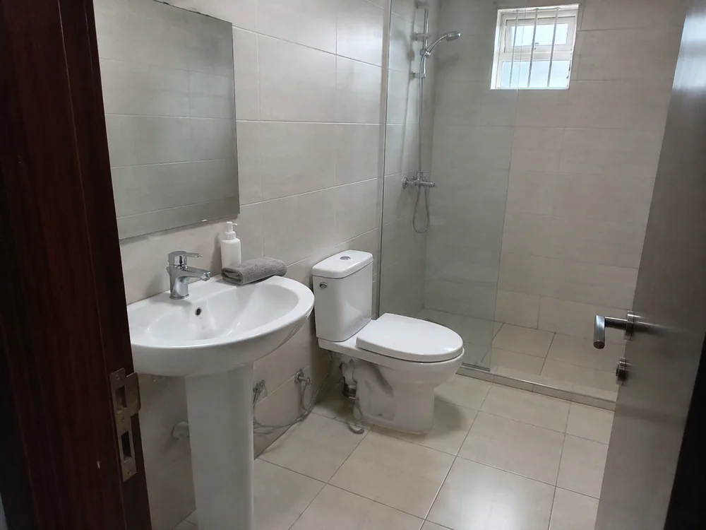 A freshly cleaned bathroom with a basin and glass shower screen